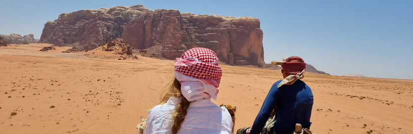 foto kameelrit in wadi rum twee mensen met doeken om hun hoofd van achteren