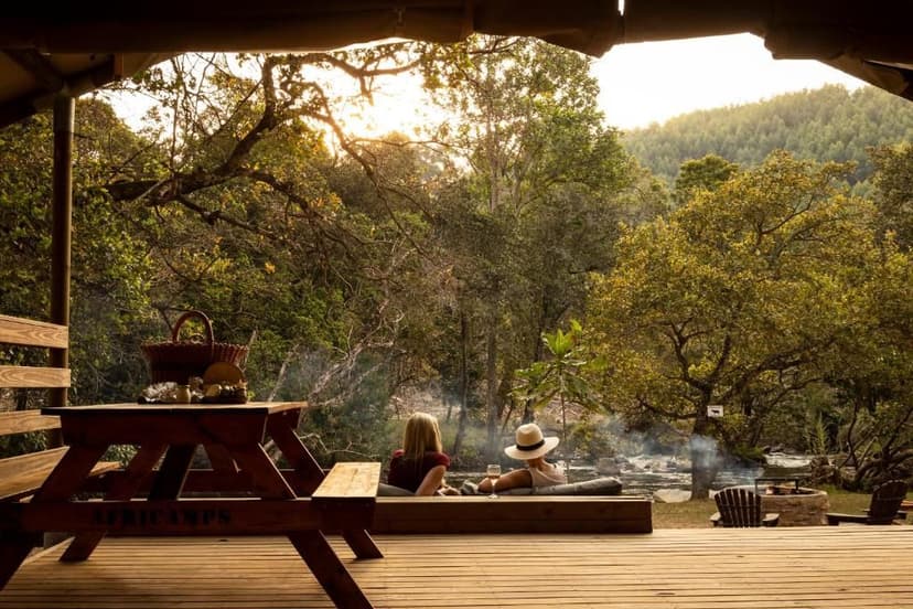 Uitzicht vanaf de glamping tent naar de natuur met in beeld een picknick tafel met een mandje erop