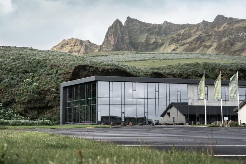 Een glazen hotel in Vik omringd door de bergen en groene natuur