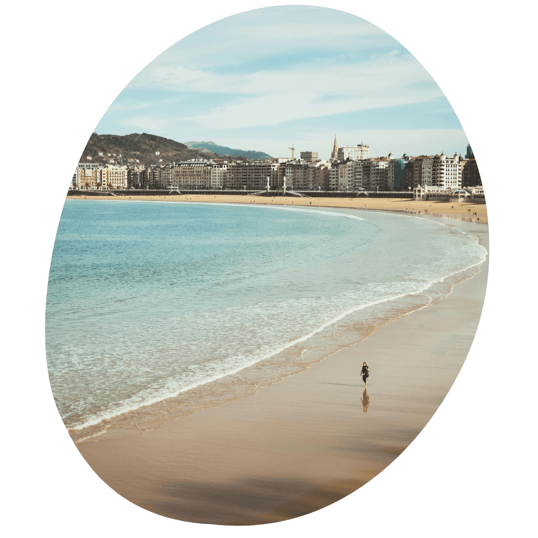 Een vrouw die loopt over het strand van San Sebastian