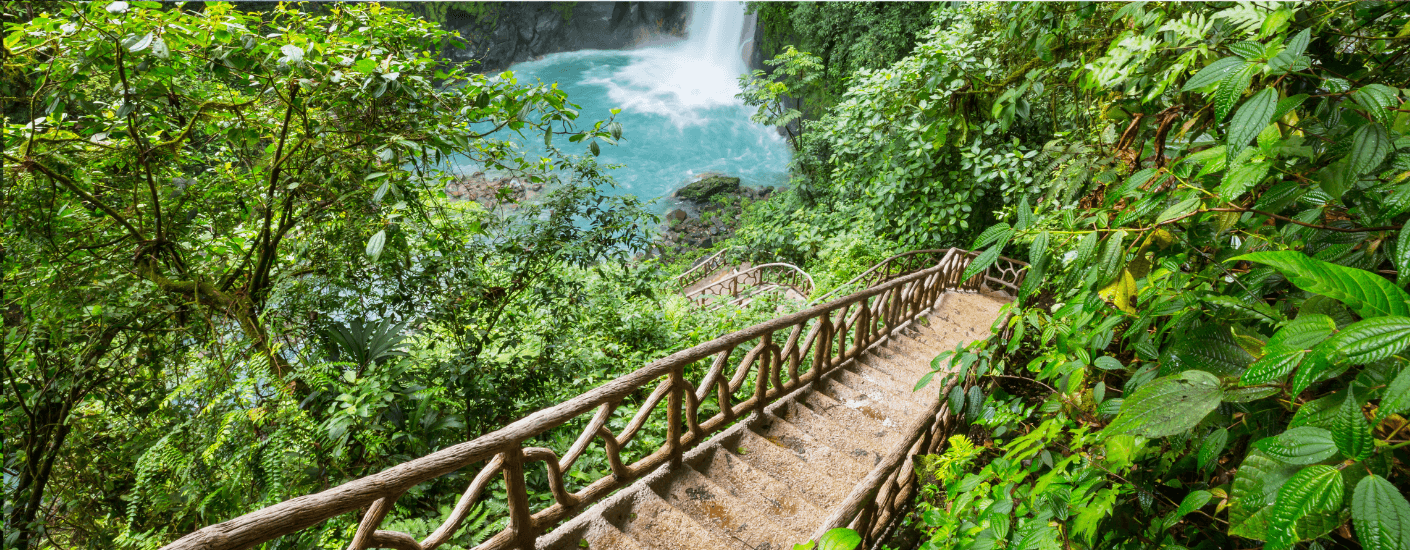 Een bruine trap die omlaag loopt naar een waterval in de jungle van Costa Rica