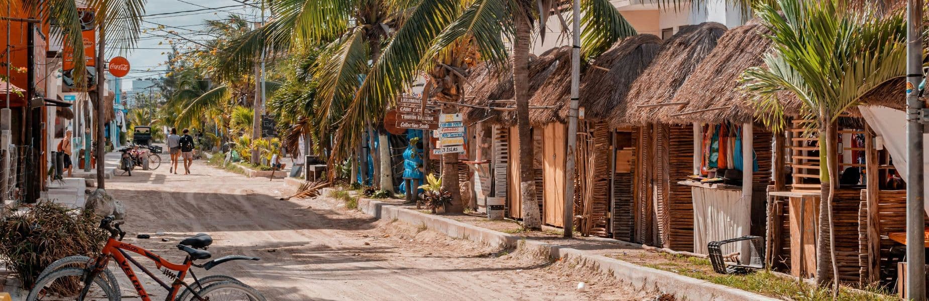 Straat in Isla Holbox met huisjes met rieten daken aan de zijkant