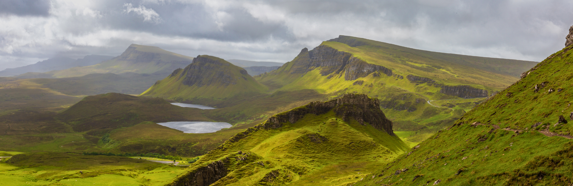Uitgestrekt groen landschap met twee vijvertjes en bergpieken in Schotland