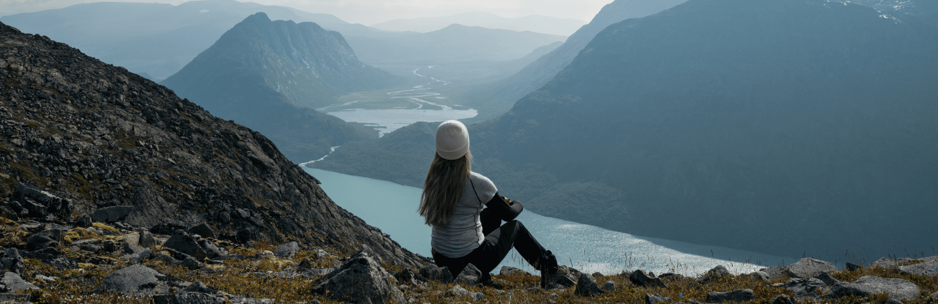 vrouw die uitkijkt over helderblauw water in het fjord