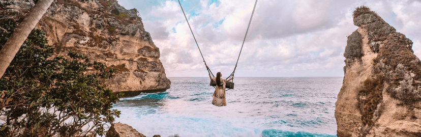 Vrouw die schommelt boven prachtig blauw water