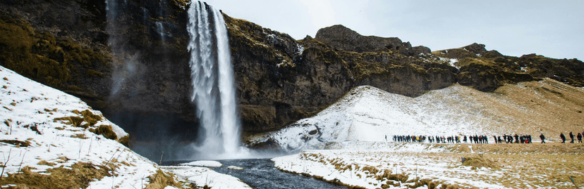 Prachtige waterval met wandelende mensen en sneeuw op achtergrond