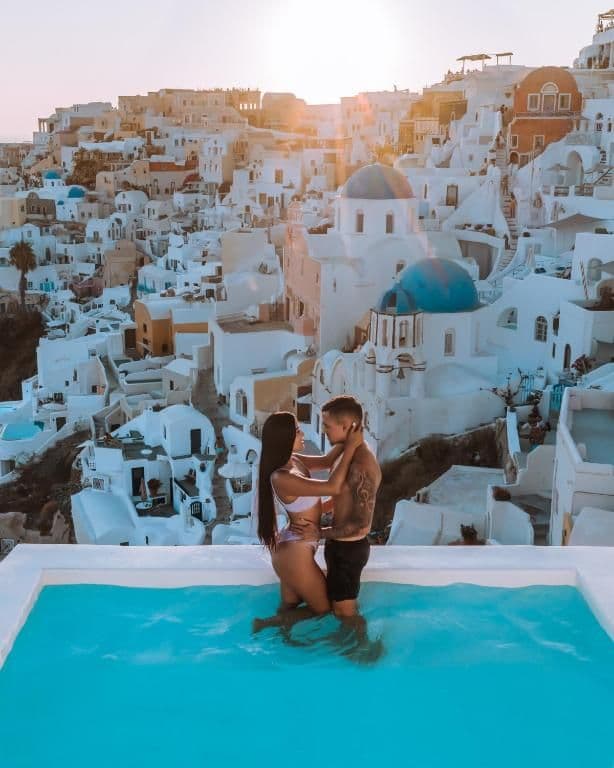 Aspaki by Art Maisons koppel in zwembad met huisjes van Santorini op de achtergond