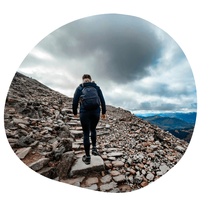 Vrouw die de Ben Nevis in Schotland beklimt, aan de rechterkant kan je genieten van het uitzicht