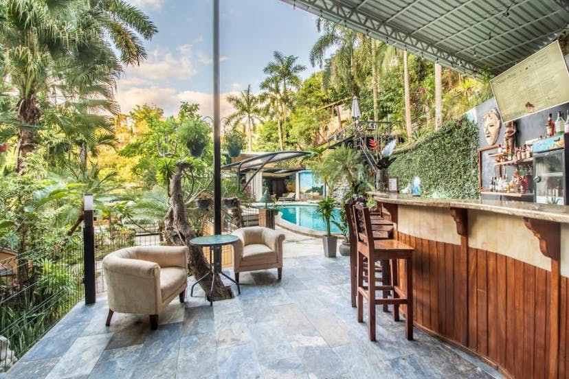 zit gedeelte met bar en zwembad van een hotel omringd door palmbomen en bos