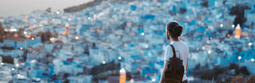 Een jongen van de achterkant die vanaf bovenaf kijkt op de blauwe stad Chefchaouen