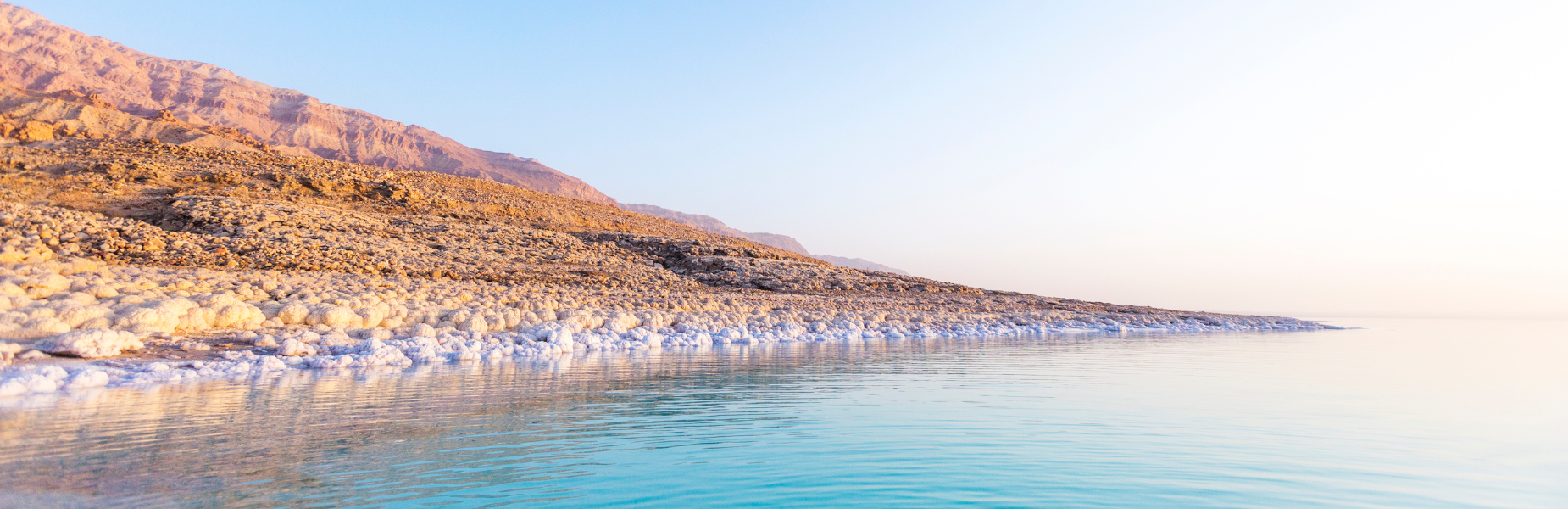 de kust van de dode zee met het droge  bergachtige landschap op de achtergrond