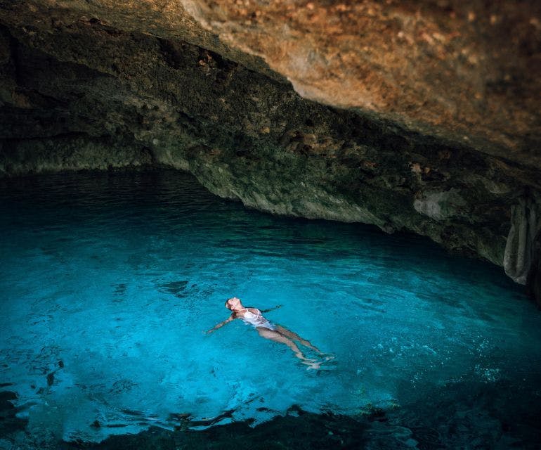 Meisje drijvend in het water in een grot